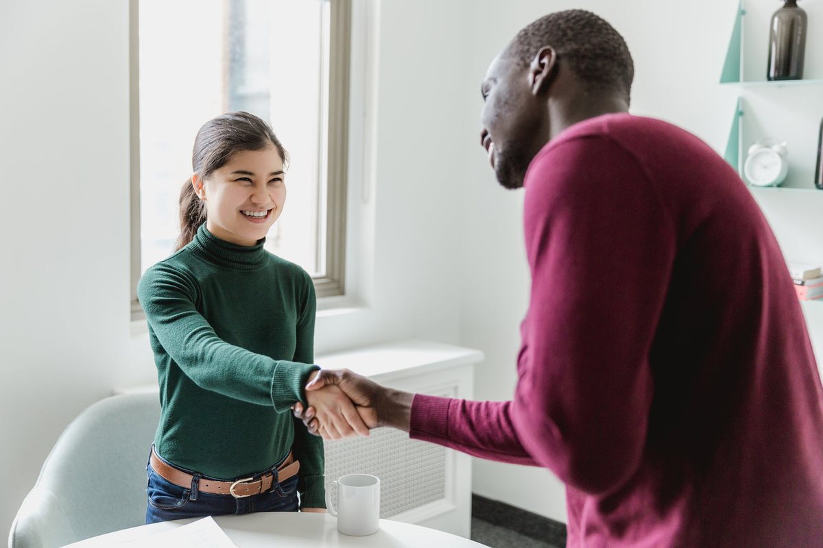 Two people shaking hands across a table after a successful interview