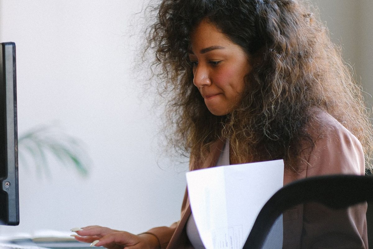 A woman reviewing paperwork at an office desk