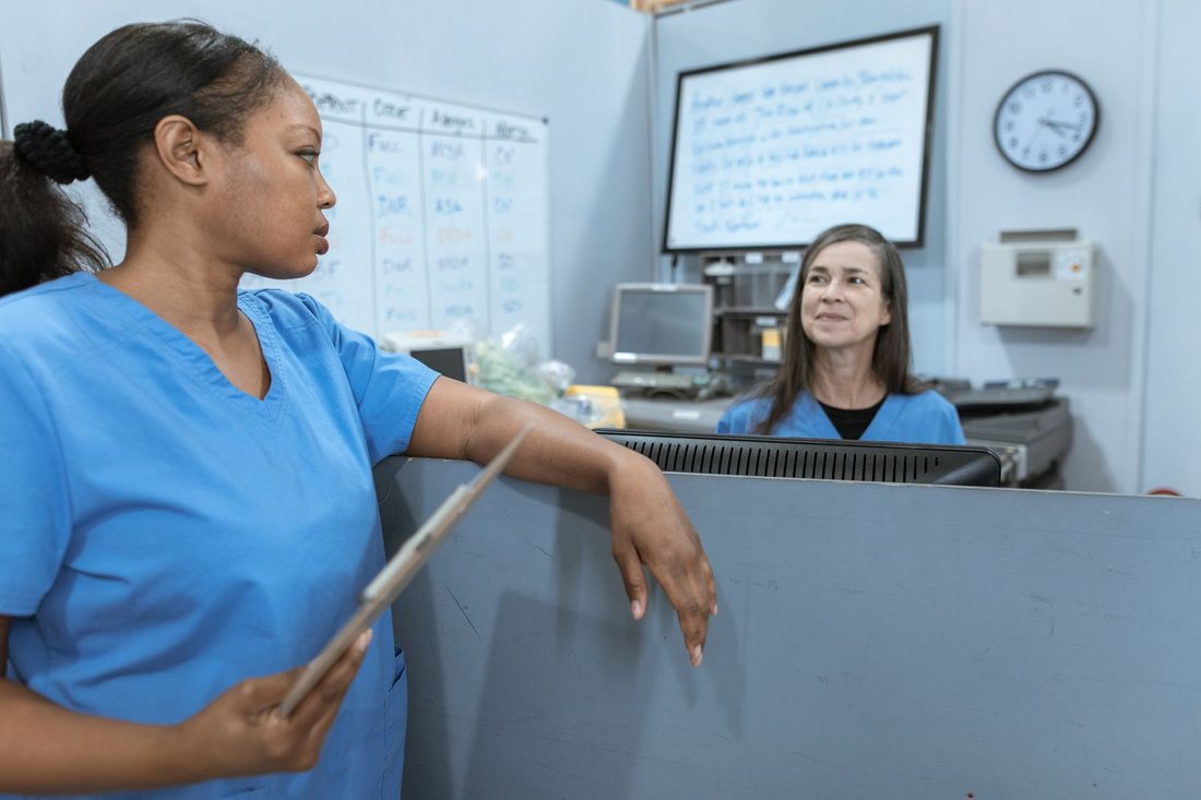 Two nurses talking at a ward station