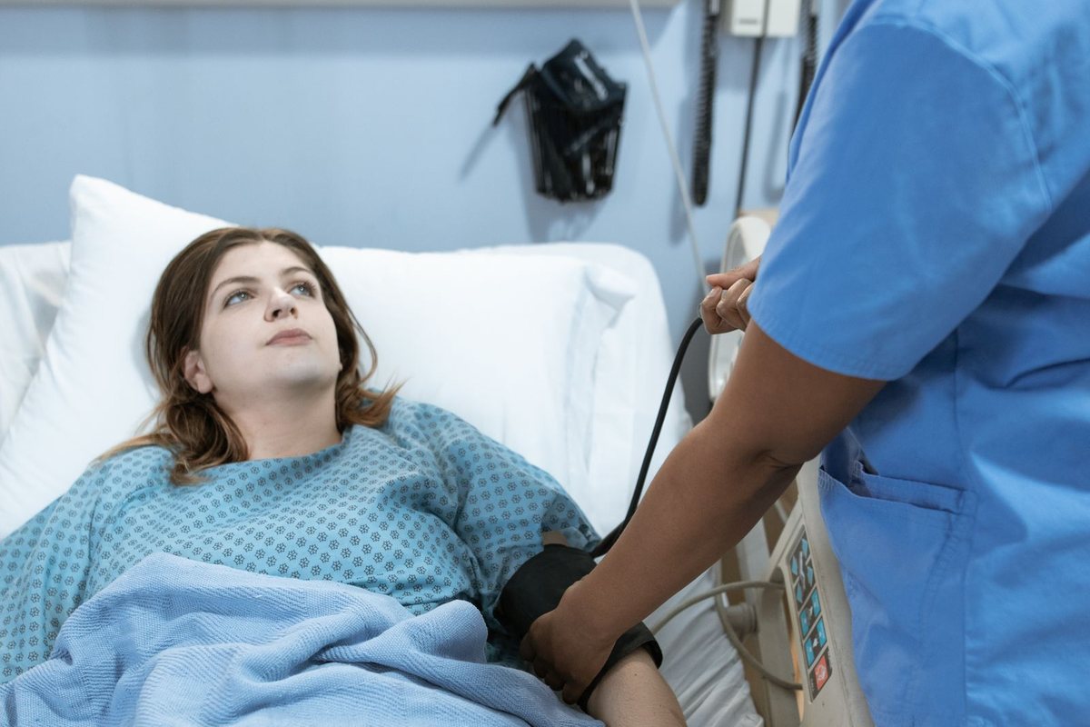 A patient in a hospital bed being checked during a ward shift
